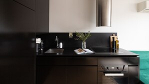 Una cocina moderna con armarios oscuros, una campana extractora de acero inoxidable, un lavamanos y una encimera con una revista.
