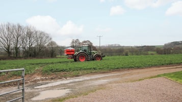 A tractor in a field with a gravel path and a metal gate.