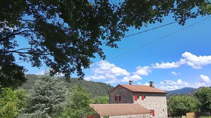 A stone building with a red-tiled roof, surrounded by greenery and a clear sky. - Character house, in a quiet location, close to the village center (Jaujac)