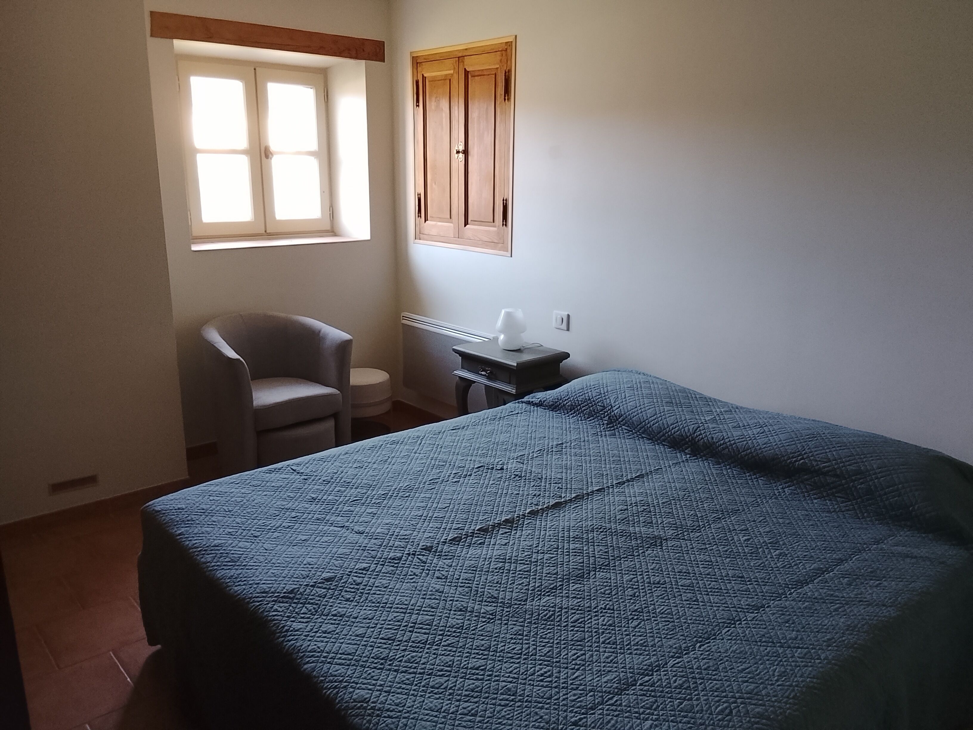 A room with a bed, a chair, a desk, a window, and a door.