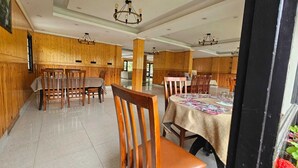 Ein Restaurant mit Holzwandverkleidung, mehreren Tischen und Stühlen.