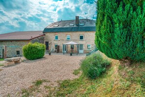 Ein Steinhaus mit Kiesweg, einer überdachten Terrasse und einer Treppe, die zum Eingang führt.