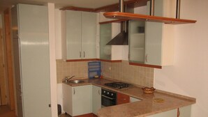 Une cuisine de taille réduite équipée d’un réfrigérateur, d’un évier, d’une cuisinière et de placards.