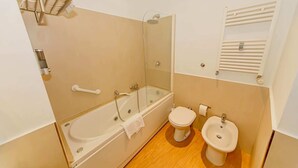 A bathroom with a bathtub, toilet, bidet, and a glass-enclosed shower. - Studio Apartment 4 pax (Roma)