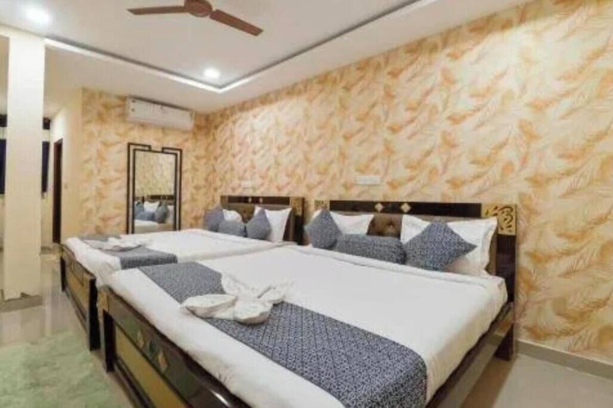A hotel room with a large bed, a ceiling fan, and a patterned wall.