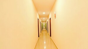 A long, narrow hallway with a shiny floor and doors on both sides. - HOTEL Q NESS  (Hyderabad)