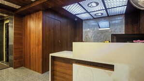 A modern bathroom with wooden cabinetry, a marble countertop, and a skylight. - HOTEL Q NESS  (Hyderabad)