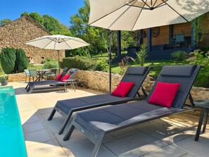 Un patio con sillones de descanso, una mesa y sombrillas.