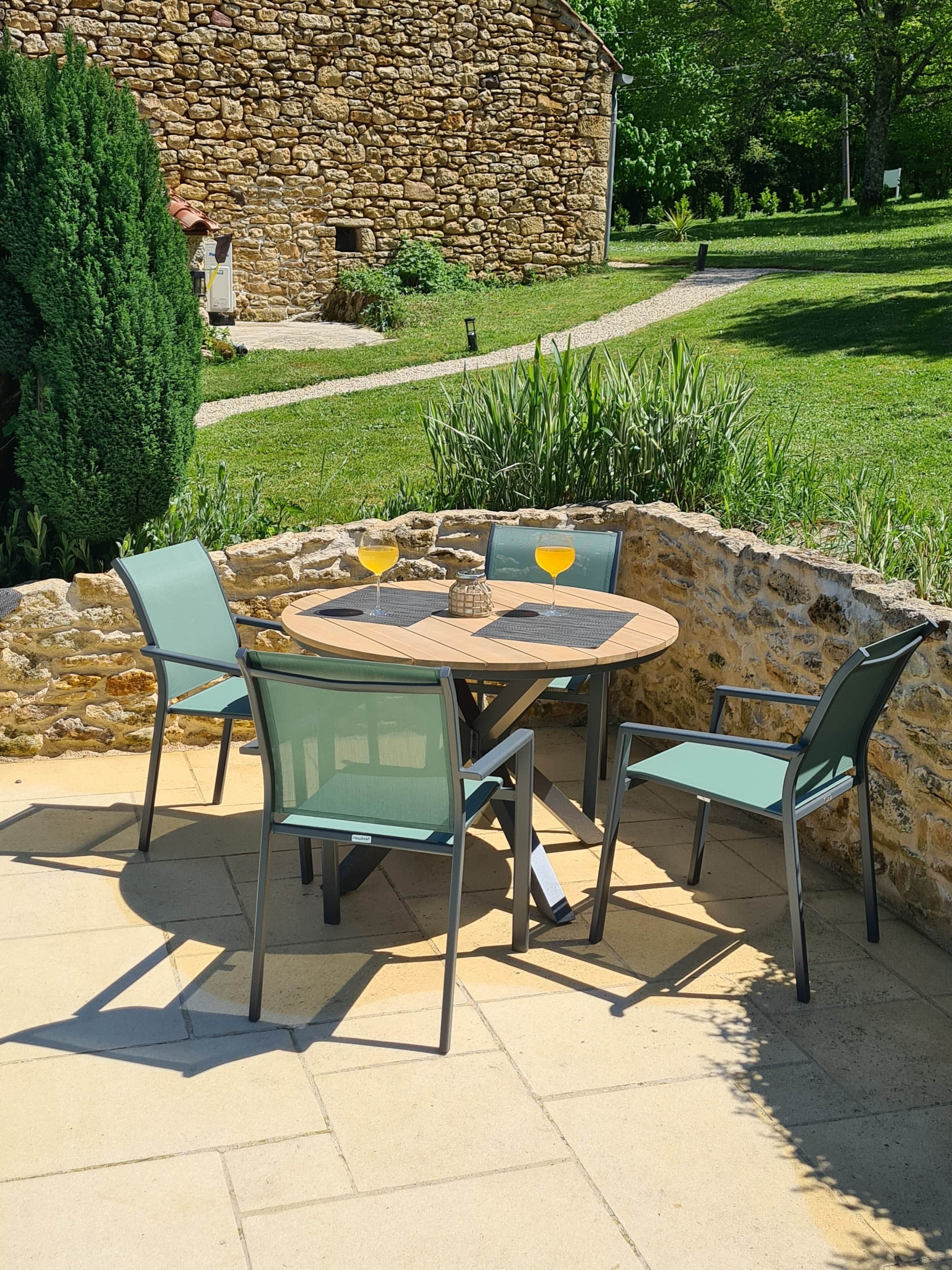 An outdoor patio with a stone wall, a round table, and four chairs.