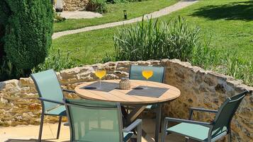 An outdoor patio with a stone wall, a round table, and four chairs.