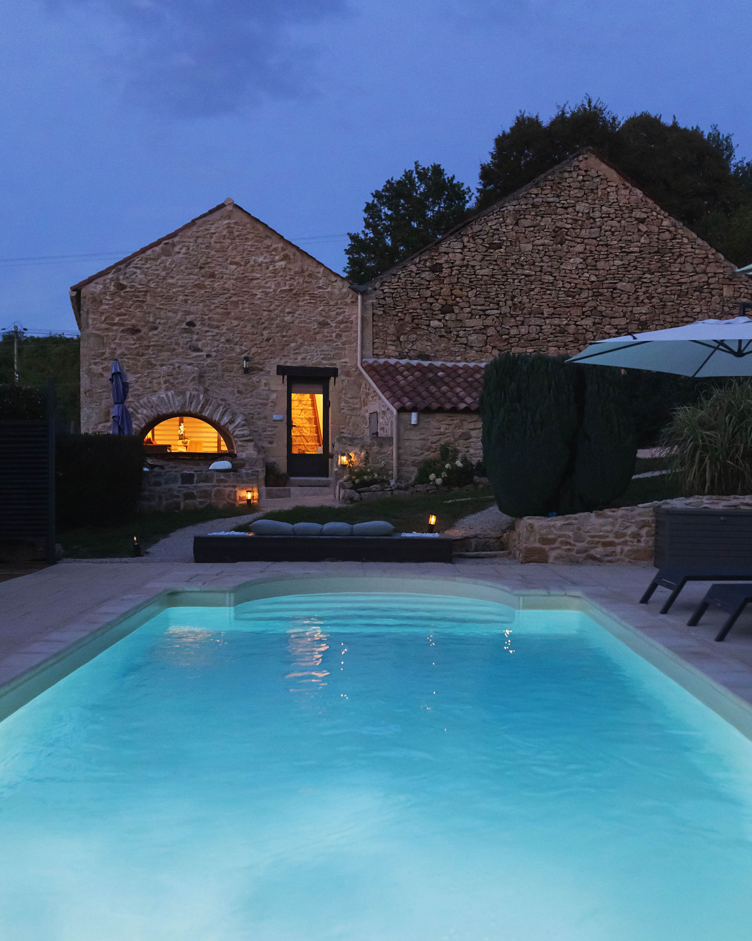 Un bâtiment en pierre avec une piscine devant.