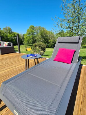 Un fauteuil confortable avec un coussin, une petite table avec une boisson et un livre.