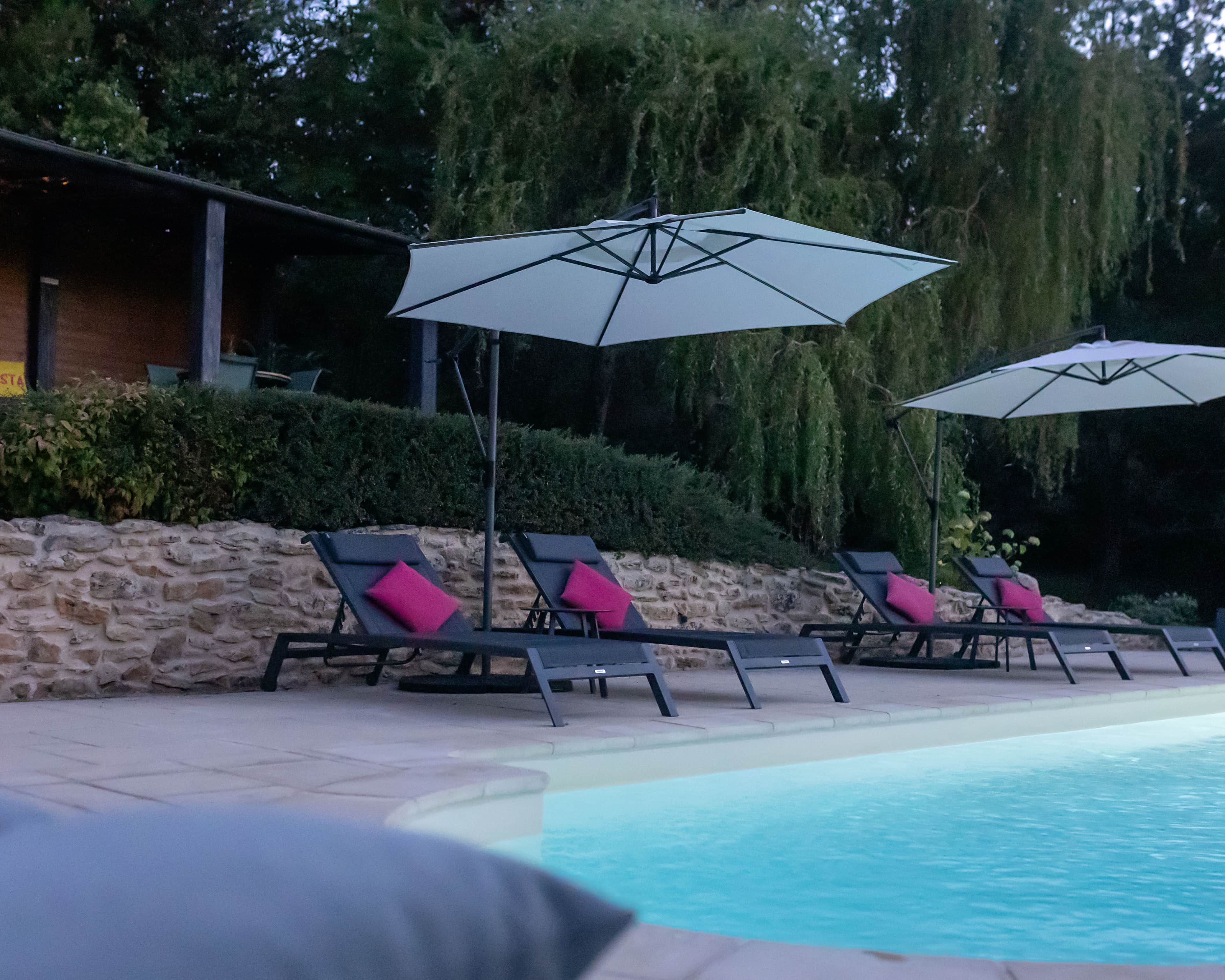 Un espace aménagé au bord de la piscine, avec des chaises longues et des parasols.