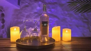 Una mesa con velas, una botella y dos vasos.