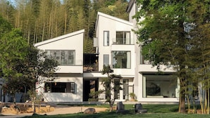 Ein modernes, zweistöckiges Haus mit großen Fenstern, einem Balkon und einem gepflegten Rasen.
