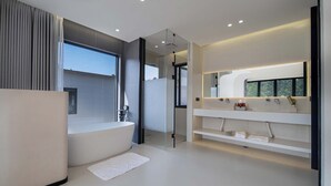 Ein modernes Badezimmer mit freistehender Badewanne, einer Duschkabine aus Glas und einem Waschtisch mit Spiegel.