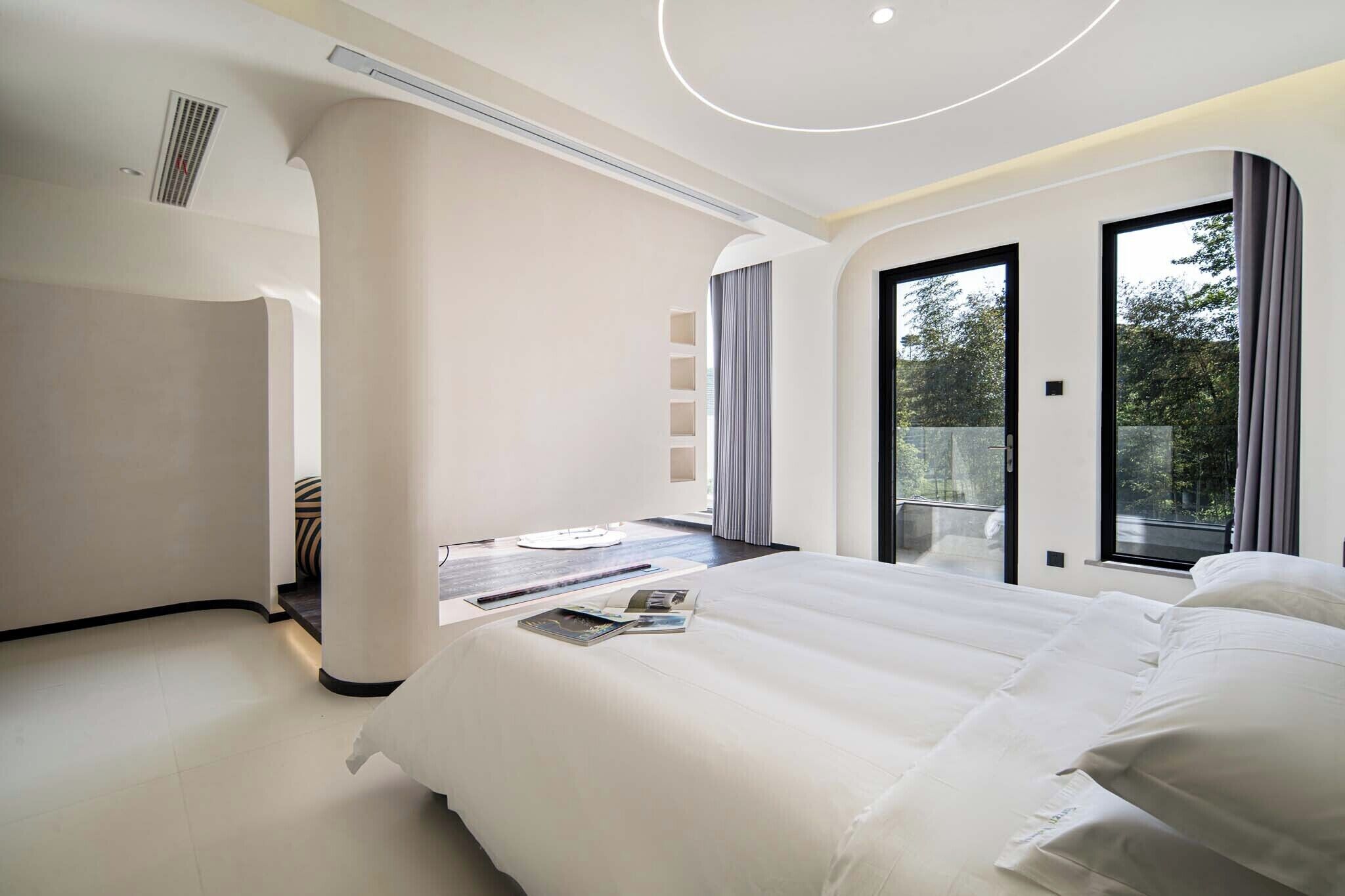 Habitación de hotel moderna con una cama grande, una mesita y vistas al exterior a través de una puerta corredera.