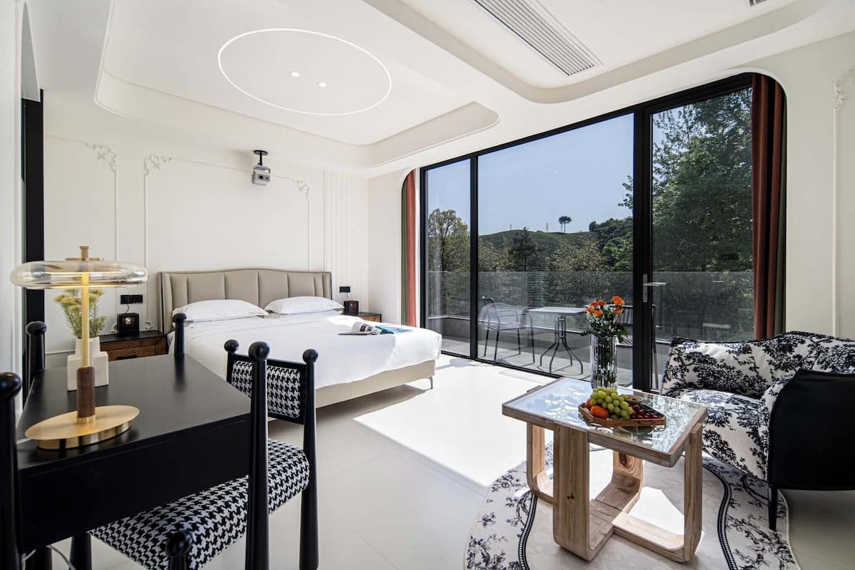 Une chambre d’hôtel moderne équipée d’un lit, d’une table à manger, d’un canapé et d’un balcon avec vue.