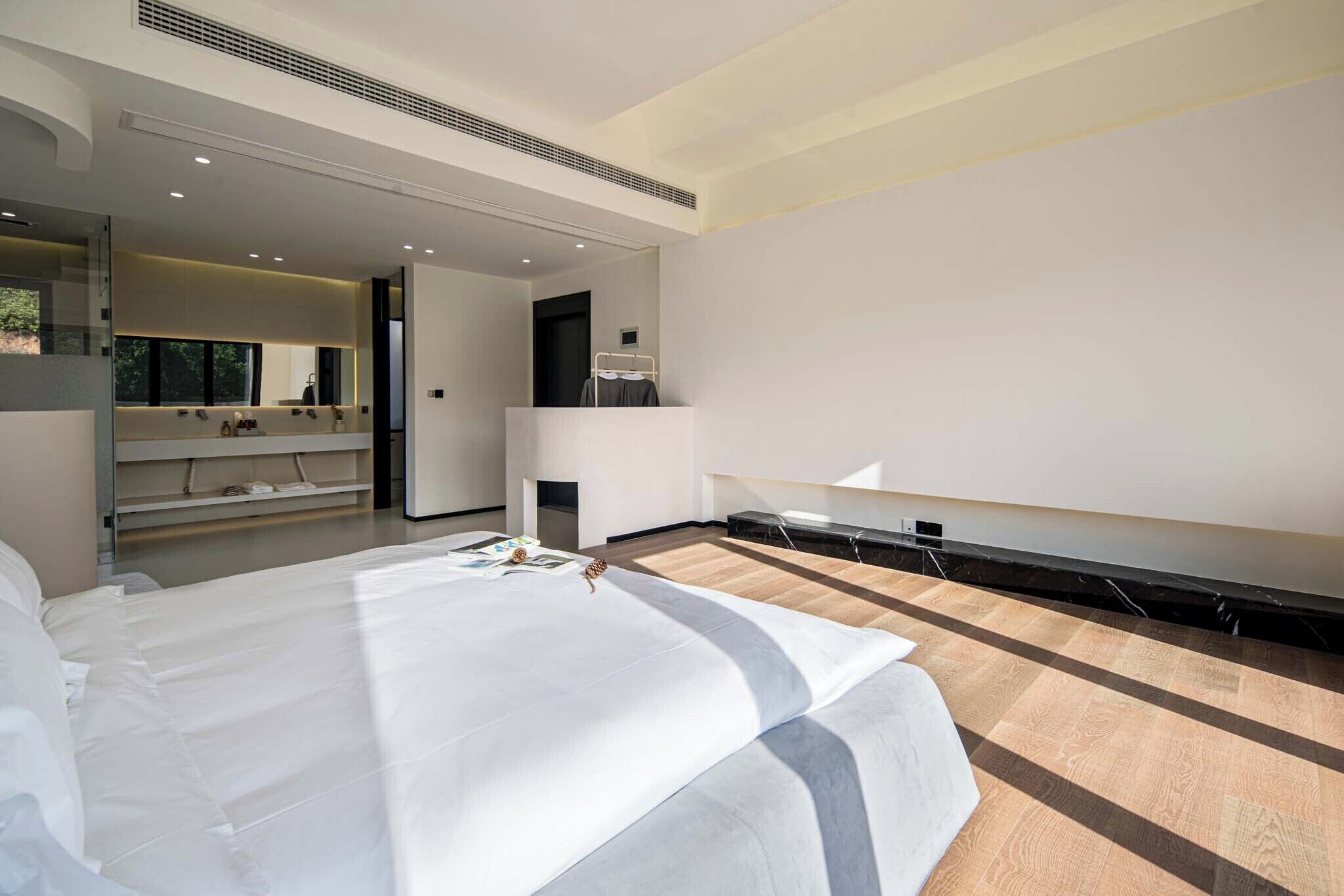 A modern bedroom with a large bed, a built-in TV, and a walk-in closet.