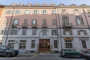 Un immeuble à plusieurs étages doté d’une entrée centrale, de balcons et d’une enseigne indiquant qu’il s’agit d’un établissement commercial.