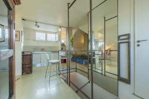 A modern kitchen with a dining area, a staircase, and a bedroom with a view.