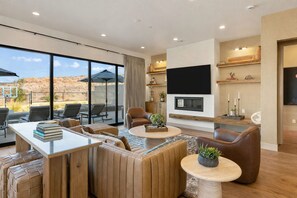 A modern living room with a large TV, comfortable seating, a fireplace, and a view of the desert. - Ever-Changing Sky: Private Pool, Large Rental! (Washington)