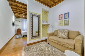 A cozy living room with a beige sofa, a patterned rug, a large mirror, and a hallway leading to a bedroom. - Spacious Apartment in Piazza Navona, Campo de' Fiori (Roma)