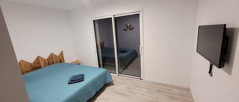 Un dormitorio con cama, puerta corrediza, televisor y cabecero de madera.