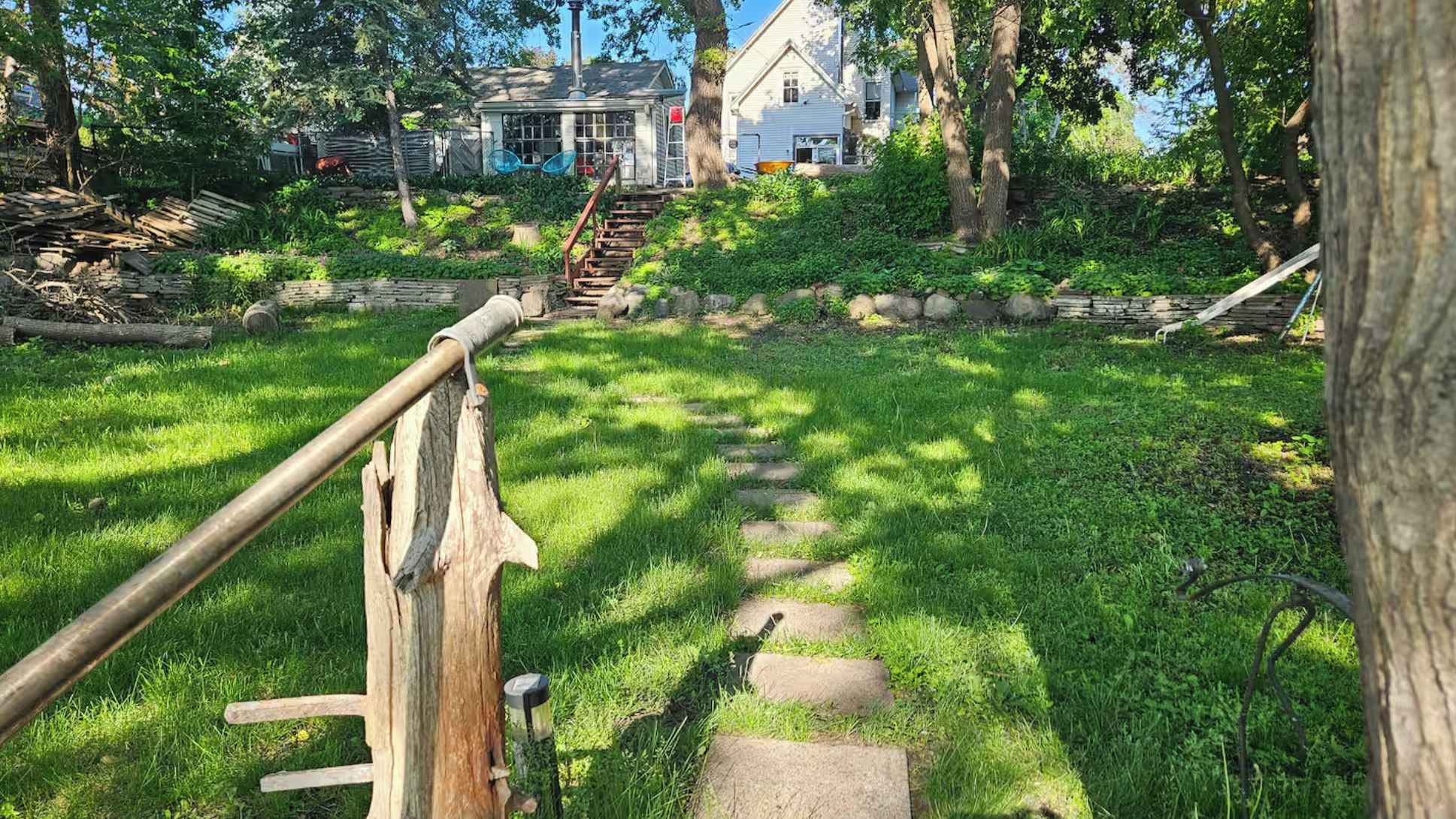 Eine Holztreppe führt zu einem Haus mit einem steinbelagten Weg.