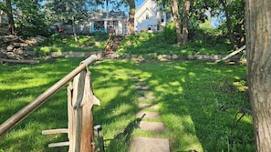 A wooden staircase leading up to a house with a stone pathway.
