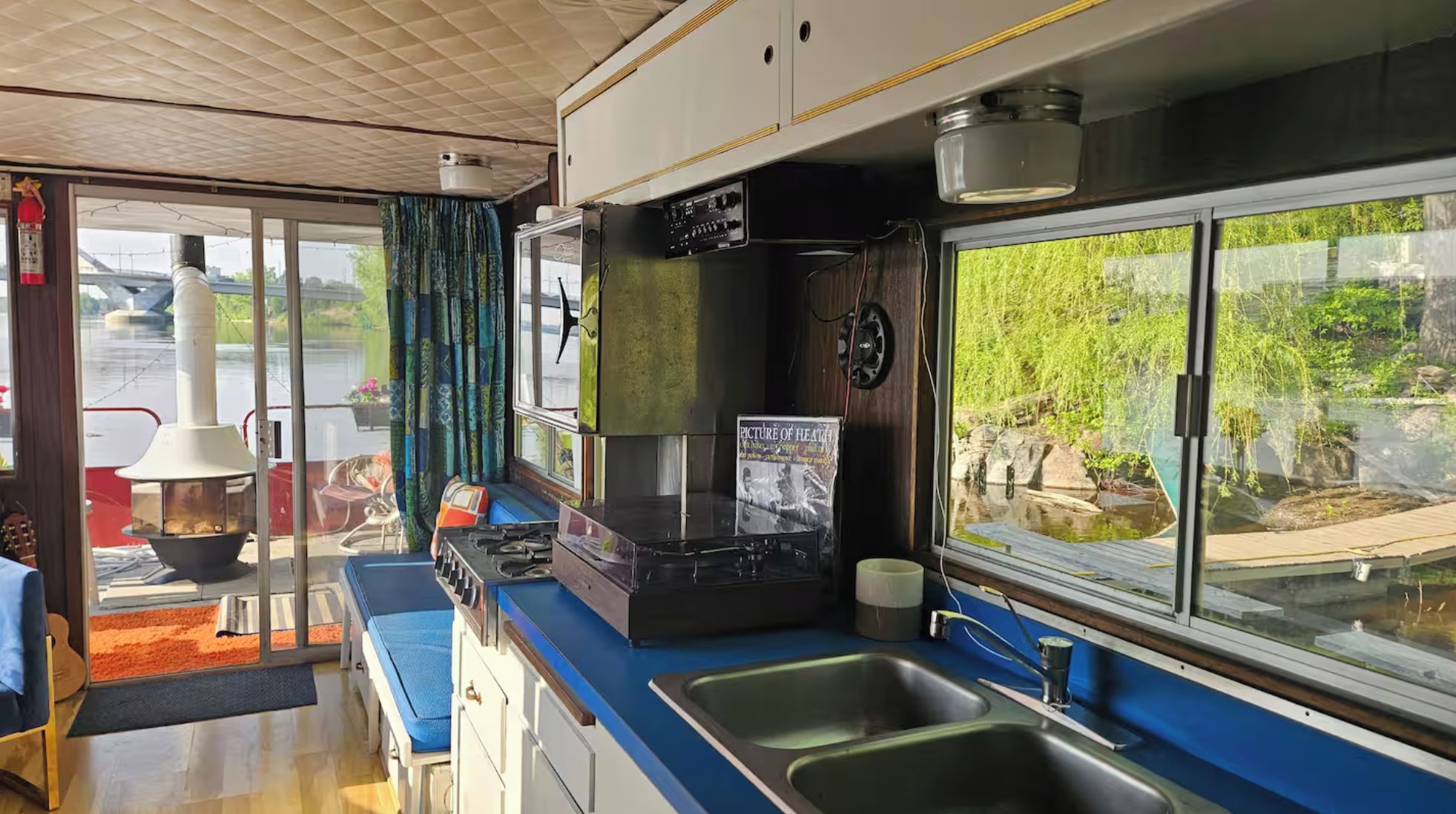 Cozinha compacta com pia, fogão e janela com vista para a natureza.