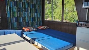 Una habitación pequeña y acogedora con una cama individual, una mesa y una ventana con vistas a zonas verdes.