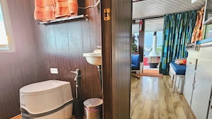 Et lille badeværelse med toilet, vask og skraldespand.
