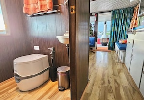 Un baño pequeño con inodoro, lavamanos y cubo de basura.