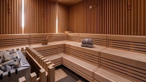 Eine Sauna mit Holzlamellen, Bänken und einem Bereich mit Steinbänken.