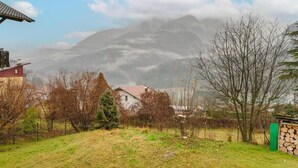 A rural landscape with a house, a stack of firewood, and a mountain in the background. - Ca' Fedon - Mountain View Terrace (Domegge di Cadore)