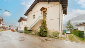 A residential building with a staircase, a small Christmas tree, and a parked car. - Ca' Fedon - Mountain View Terrace (Domegge di Cadore)