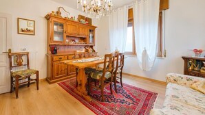 A dining area with a wooden table and chairs, a chandelier, and a red patterned rug. - Ca' Fedon - Mountain View Terrace (Domegge di Cadore)