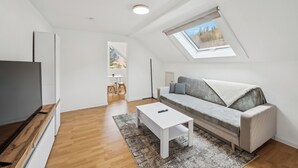 Uma sala de estar moderna com sofá, mesa de centro, TV e claraboia.