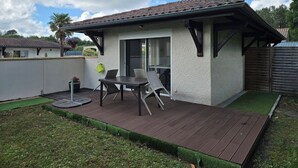 Um pátio com mesa e cadeiras, um pequeno jardim e um edifício com telhado de telhas.