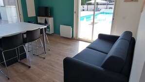 Um espaço de estar moderno com área de refeições, um sofá e vista para uma piscina.