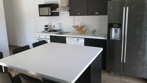 Uma cozinha moderna com geladeira de aço inoxidável, micro-ondas embutido e cafeteira.