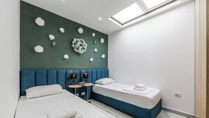 Habitación de hotel con dos camas, un tragaluz y un muro decorativo.