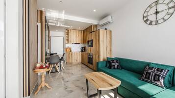 Una cocina moderna con armarios de madera, un sofá verde, una mesa de centro de madera y un reloj de pared.