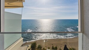 Un balcón con vista al océano, cielo despejado y el sol reflejado en el agua.