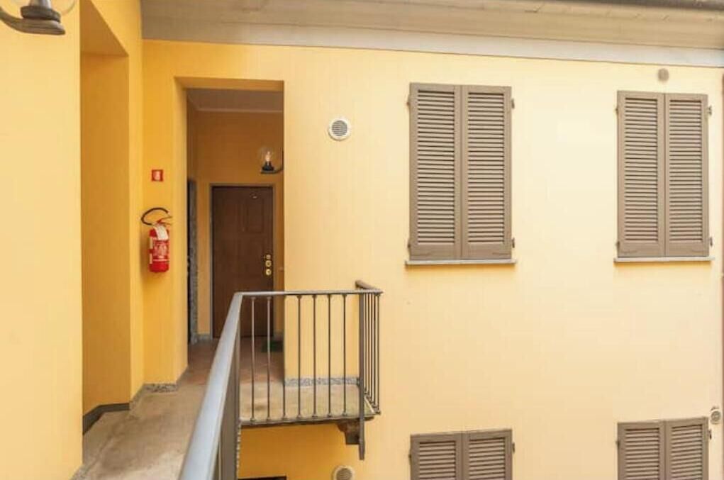 Un bâtiment jaune avec une porte, un extincteur et des volets aux fenêtres.