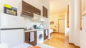 A compact kitchen with a washing machine, a microwave, and cabinets. - AP12 NICE APARTMENT IN DOWNTOWN (Milano)