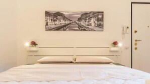 A hotel room with a bed, a nightstand, a wall-mounted picture, and a door. - AP12 NICE APARTMENT IN DOWNTOWN (Milano)