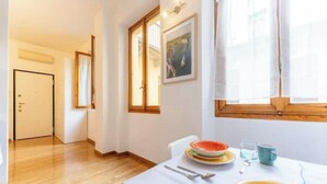 A dining area with a table set for two, a window with curtains, and a door in the background. - AP12 NICE APARTMENT IN DOWNTOWN (Milano)