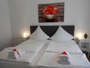A hotel room with a bed, two bedside tables, a wall-mounted artwork, and neatly folded towels on the bed.